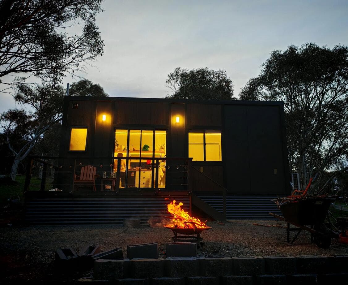 Anywhere Homes cabin beside a firepit at dusk